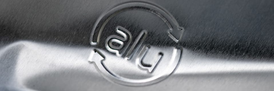 Shiny aluminum recycling symbol on metal.
