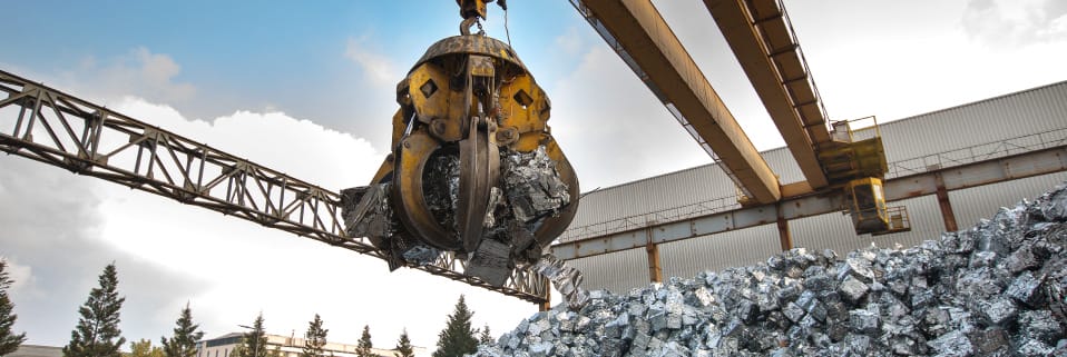 Grapple crane lifting scrap aluminum at recycling.