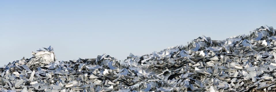 Mound of scrap aluminum against a clear sky.
