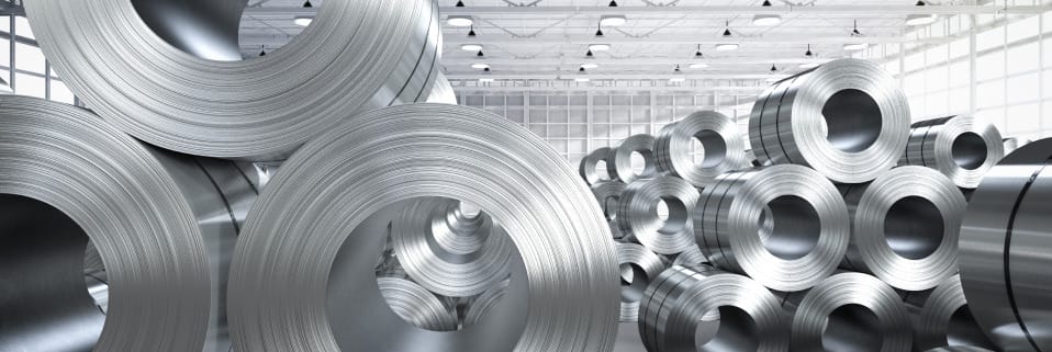 Warehouse storing coils of steel with industrial lighting overhead, symbolizing bulk steel storage or distribution.